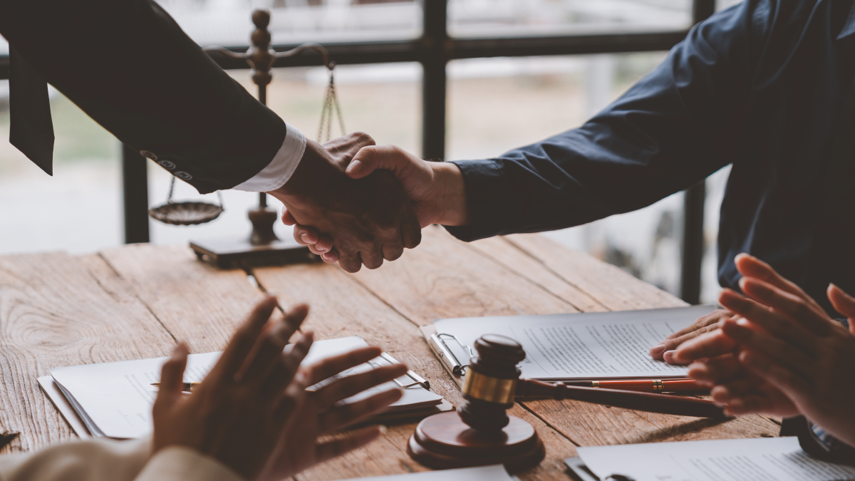 A personal injury attorney shaking hands with a new client their received from a legal referral. 